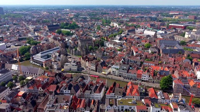 Wide horizontal aerial drone video of Ghent historic center, Gravensteen castle, Leie river canal, red brick roofs, and city panorama in East Flanders, Belgium on sunny summer afternoon