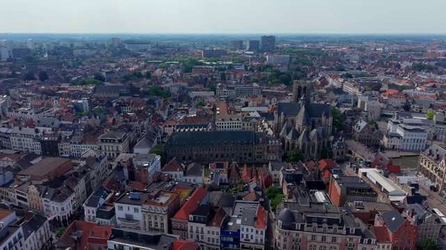 Wide horizontal aerial drone video of Ghent historic center, Saint Nicholas Church, Het Pand monastery, rooftops, and cityscape panorama in East Flanders, Belgium on sunny summer afternoon