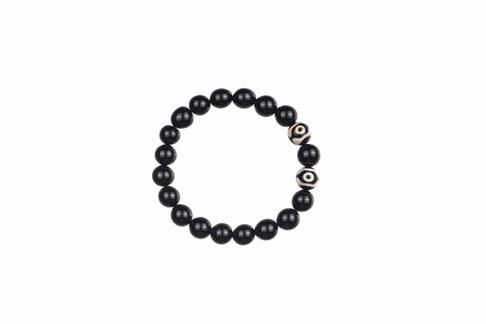 Black agate beaded bracelet with tibetan dzi eye beads isolated on a white background, minimalist amulet talisman jewelry photography with copy space