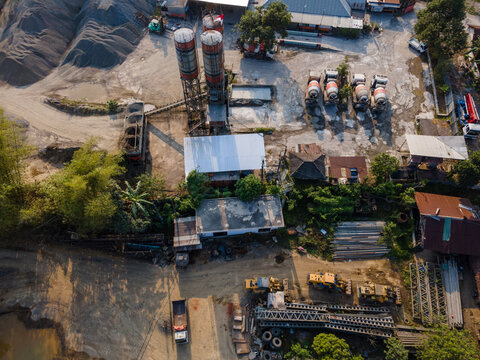 Aerial view of a concrete batching plant with industrial silos, cement mixer trucks, and construction equipment in Cilongok, Central Java, Indonesia.