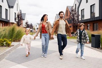 Fototapeta premium Family walking hand in hand in modern neighborhood