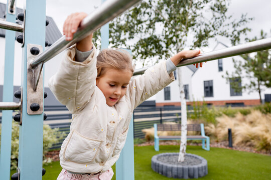 Young girl hanging on monkey bars in playground
