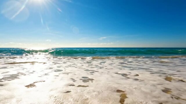 Tropical ocean waves crashing on golden sand beach under bright sunny sky