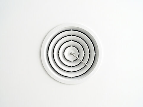 White circular ceiling air diffuser vent grille mounted on plain white background