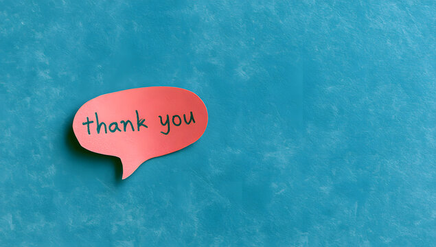 A miniature speech bubble card expressing gratitude in blue with handwritten notes on a textured background, showing positive sentiments and kindness