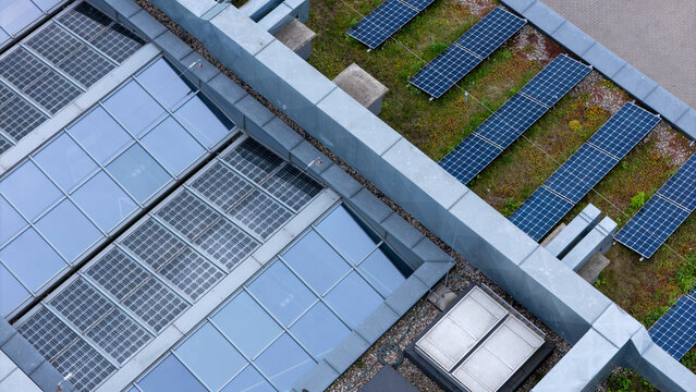 Aerial view of a green roof featuring rows of solar panels and a large glass skylight structure in Gdansk, Poland.