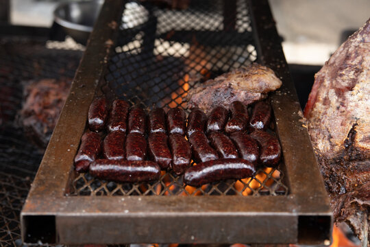 Traditional morcilla blood sausages are cooked on a metal street grill over an open fire. High in animal fat and protein for LCHF, keto, and carnivore diets.