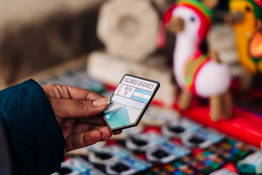 Hand holding a salinas grandes and ruta 52 souvenir magnet, featuring the argentina flag, offering a memento of travel and a destination from the jujuy province