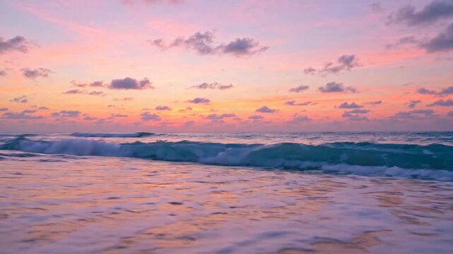 Tropical beach sunset with gentle ocean waves rolling onto sandy shore at dusk