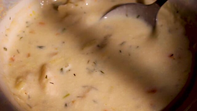 Creamy seafood chowder with shrimp and vegetables being served with a spoon