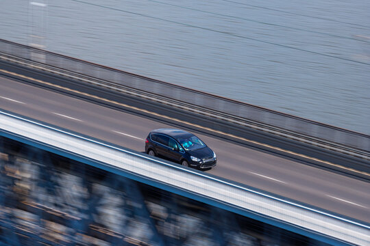 Aerial view of a black car driving on a bridge over water in Poland.