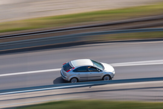 Aerial view of a silver hatchback car driving on a highway with motion blur effect in Poland.