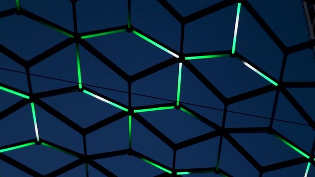 Abstract geometric pattern of glowing green neon lights in a hexagonal grid structure against a dark blue night sky