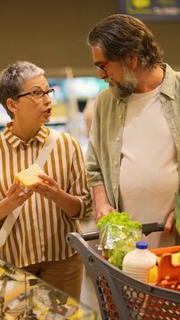 Senior couple buying cheese in the supermarket