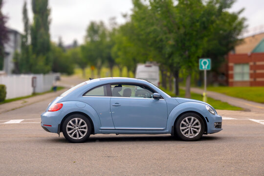 Calgary, AB, Canada - Sept 15, 2026: Side view profile of a light blue Volkswagen Beetle parked on a residential suburban street.