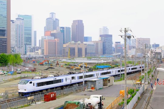高層ビル群と再開発エリアを背景に走る特急列車