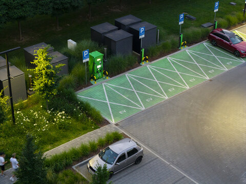 Aerial view of electric vehicle chargers and dedicated EV parking spaces surrounded by landscaped green infrastructure