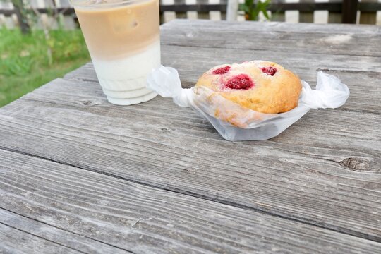 ラズベリーマフィンとアイスカフェオレ。屋外の木製テーブル