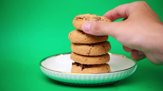  Hand serving and taking a chocolate chip cookie from a stacked plate on green screen background