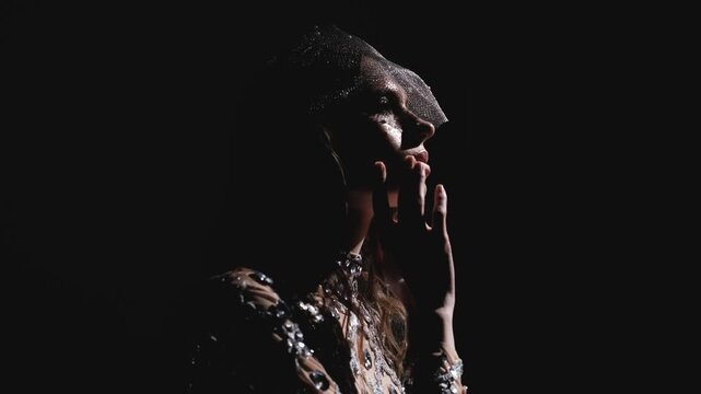 Mysterious woman in sparkling rhinestone veil surrounded by smoke