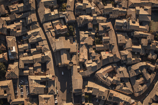 Aerial view of Orvieto with dense terracotta-tiled rooftops, narrow stone streets, and warm golden hour sunlight illuminating the medieval architecture in Orvieto, Umbria, Italy.