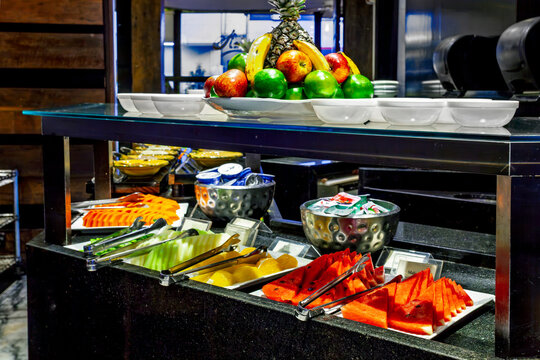 Luxury hotel breakfast buffet featuring a fresh tropical fruit station with sliced watermelon, melon, papaya, and whole fruits.