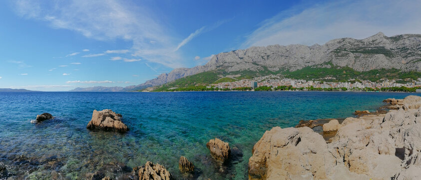 Panoramic view of the turquoise water of the Adriatic Sea and the town of Makarska, Croatia, with the Biokovo mountain in sunny summer day
