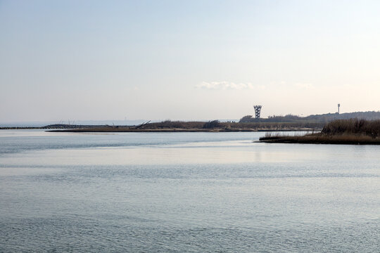 Calm waters of the Adige river mouth with the Foce dell'Adige Panoramic Tower on the horizon, Isola Verde, Chioggia, Veneto, Italy