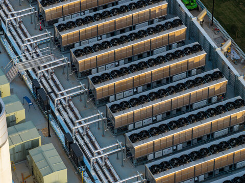 Aerial view of industrial data center cooling units and heat rejection equipment with rows of fans and metal piping on a rooftop in Sydney, New South Wales, Australia.