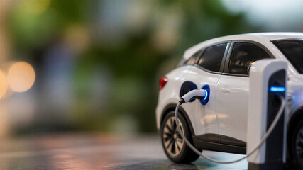 Fototapeta premium Close up of electric charger miniature car, small model of white car on the station, horizontal banner, free space for text, copy space