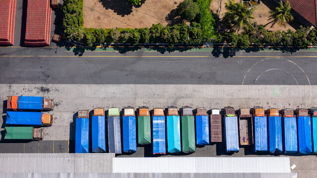 Aerial view of a line of parked trucks with colorful tarpaulin covers in a logistics yard in Salatiga, Central Java, Indonesia.