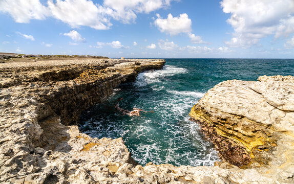 Scenic view of the rocky limestone cliffs and crashing turquoise ocean waves at Devil's Bridge National Park on the island of Antigua.