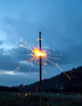 Sparkler fireworks burst light night blue sky glowing sparkler creates bright burst against dark mountain landscape, capturing celebration and wonder during outdoor evening scene