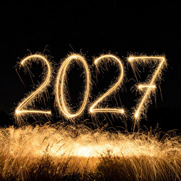 Sparkler number formed above glowing grass against black background, creating bright celebration scene with energy, light trail, and festive atmosphere for new year concept