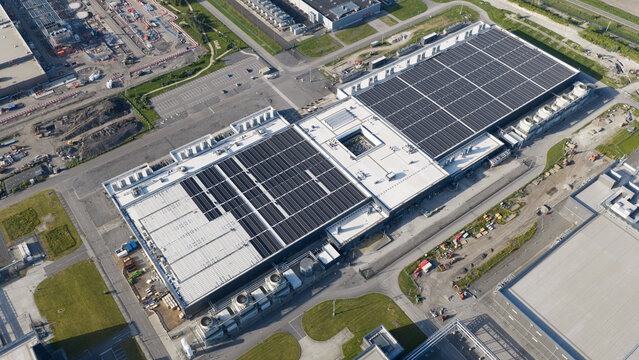 Aerial view of data center complex featuring large industrial buildings, cooling systems, and solar panels in Saint-Ghislain, Region wallonne, Belgium.