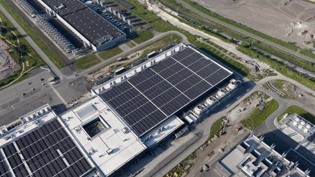 Aerial view of the Google data center featuring large industrial buildings with solar panels on the roofs and cooling units in Saint-Ghislain, Region wallonne, Belgium.