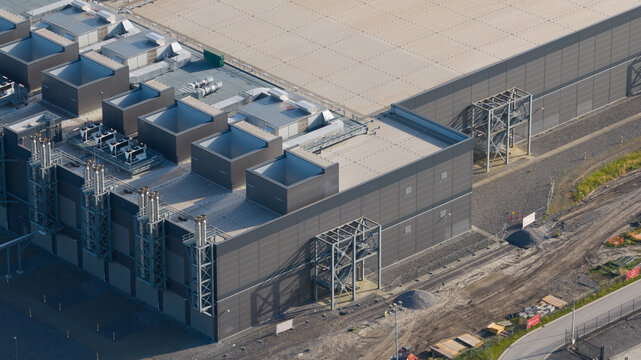 Aerial view of data center complex featuring large industrial buildings, cooling systems, and solar panels in Saint-Ghislain, Region wallonne, Belgium.