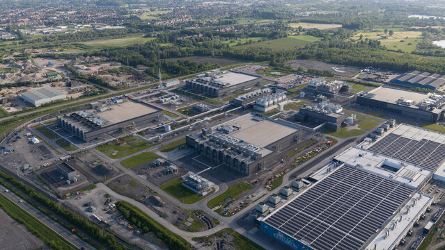 Aerial view of data center complex featuring large industrial buildings, cooling systems, and solar panels in Saint-Ghislain, Region wallonne, Belgium.