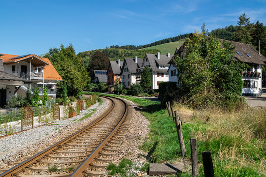 Scenic railway track curving through a picturesque Black Forest village surrounded by green hills, Germany.