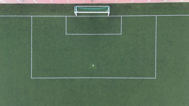 Aerial view of a soccer field with white markings and a goal net on green artificial turf in Riga, Latvia.