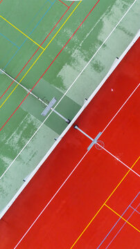 Aerial view of a vibrant sports court with contrasting green and red surfaces and white court markings in Riga, Latvia.