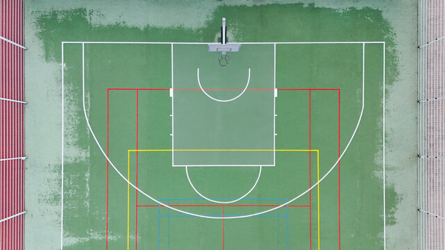 Aerial view of a colorful outdoor basketball court with painted lines and a hoop in Riga, Latvia.