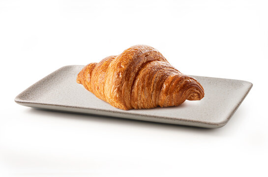 Golden-brown, butter croissant served on an elegant rectangular cream ceramic plate. Minimalist food photography perfect for bakery, breakfast, and cafe concepts. Isolated on white.
