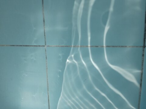 light caustics water ripple reflection on blue ceramic tile wall texture