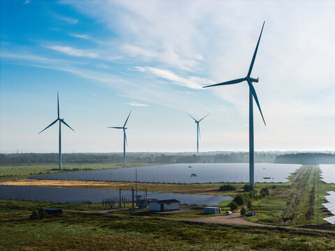 Aerial view of the Targale wind and solar park featuring large wind turbines and extensive solar panel arrays set in a green landscape in Targale, Ventspils Municipality, Latvia.