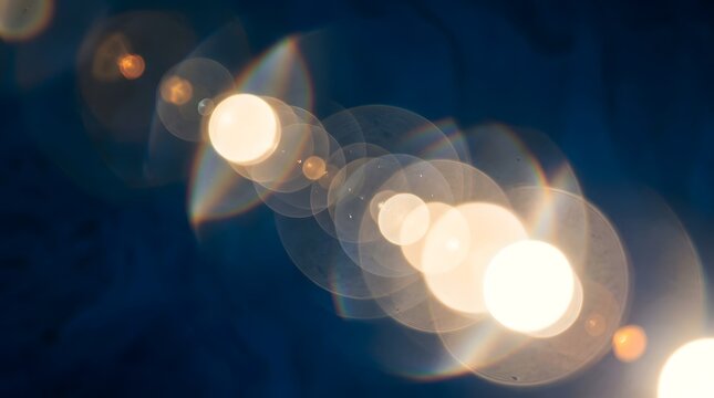 Abstract golden lens flare circles on dark blue background with light bokeh glowing circles light effect optical flare shimmering ligh