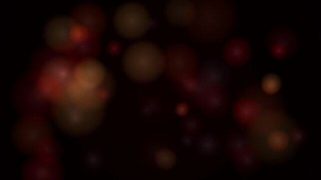 A soft bokeh loop creating a warm overlay with gentle red and gold glows over a deep black background
