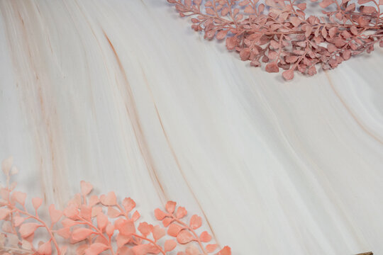 Flowing abstract marbled texture in cream tones with pink dried leaves framing the corners.