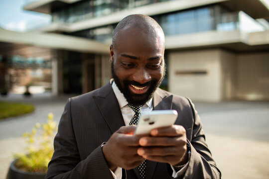 Smiling businessman using smartphone outside office building