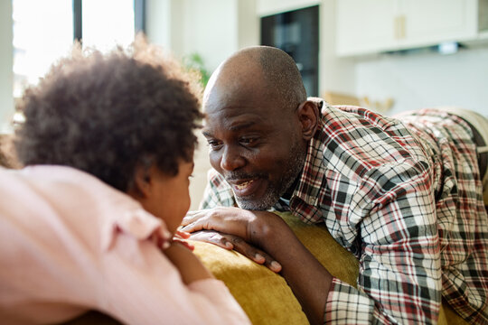 Smiling father talking with child at home